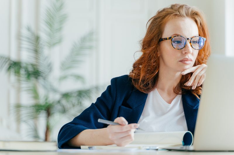 Serious experienced female coach makes records in notepad, focus