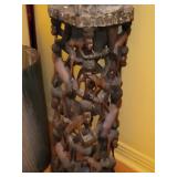 sculpture a carved figure playing percussion instrument with burlap clothes and encrustation.