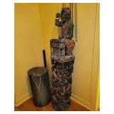 sculpture a carved figure playing percussion instrument with burlap clothes and encrustation.