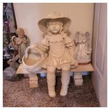 Garden statue of a girl sitting on a bench holding a basket