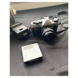 a vintage Canon AE-1 35mm SLR film camera with a flash attachment and a "Popular Filter" accessory b