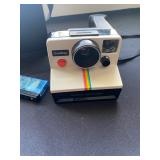 a vintage Polaroid OneStep Land Camera, known for its iconic rainbow stripe. It was the flagship mod