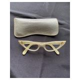 a pair of vintage cat-eyeglasses, a popular style from the 1950s and 1960s, The frames are a light c