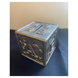 a vintage silver-plated ABC block coin bank, often made by brands like Raimond or Leonard. 