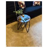industrial round end table featuring a wood-look top and a V-shaped black metal magazine rack
