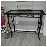 Console table with a black metal base and glass top