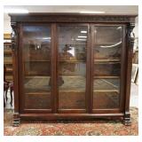 1009	CARVED HORNER MAHOGANY 3 DOOR BOOKCASE, HAS GRAIN CARVING & CLAW FEET & LEAF & SCROLL BAND ACRO
