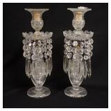 1228	PAIR OF CUT CRYSTAL CANDLESTICKS W/ PRISMS. ONE OF THE CANDLESTICKS HAS A BROKEN TOP RIM (PIECE