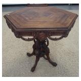 1108	HEXAGONAL LAMP TABLE, HAS CARVED SKIRT W/SWAGS ON ELABORATE CARVED PEDESTAL, 29 IN ACROSS X 30 