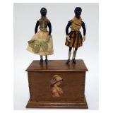 1149	ANTIQUE CLOCKWORK DANCING DOLLS. 2 DANCING FOLK ART STYLE DOLLS ON TOP OF A WALNUT CASE WITH AN
