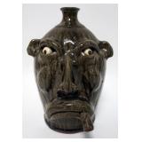 1153	JEFF HANDLING GROTESQUE FACE JUG, UGLY FACE JUG, MAN SMOKING A CIGAR WITH A TOBACCO SPIT GLAZE.