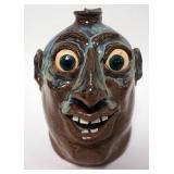 1162	TIM FLINN GROTESQUE FACE JUG, JUG WITH MULTI COLOR DRIP GLAZE, SIGNED AND DATED ON BOTTOM, 2001