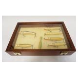 1222	GROUP OF 7 JOHN HENRIKSEN PLUGS, FISHING LURES IN WALNUT DISPLAY CASE, 12 IN X 18 IN X 3 3/4 IN