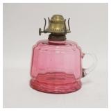 1094	CRANBERRY GLASS KEROSENE LAMP, APPLIED CLEAR HANDLES, INTERIOR RIBBING, 5 3/4 IN HIGH