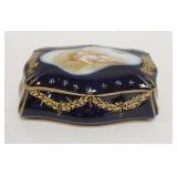 1206	HAND PAINTED PORCELAIN DRESSER BOX, COBALT BLUE AND GOLD WITH CHERUB. 6 1/2 IN X 4 IN X 2 1/2 I