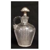 1064	CUT GLASS JUG W/STERLING SILVER OVERLAY STOPPER, HAS RIM CHIPS & A CHIP ON THE UNDERSIDE, 8 IN 