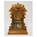 1194	GILBERT CARVED OAK GINGERBREAD CLOCK W/PAINTED DOOR, HAS PARTIAL LABEL ON THE REVERSE, 13 IN WI