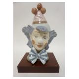1143	LLADRO CLOWN HEAD, COMES W/ WOODEN BASE, 9 1/2 IN HIGH