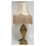 1281	METAL LAMP W/CHERUB HANDLES, PAINTED GOLD, BROCADE CLOTH SHADE W/FRINGE, 36 IN HIGH