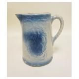 1280	BLUE STONEWARE PITCHER W/FRUIT DECORATION, HAS A FAINT HAIRLINE IN THE BASE, 8 1/4 IN HIGH