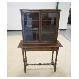 1179	WILHELM STEP BACK CABINET, 2 GLASS DOORS & DRAWER, TURNED LEGS & STRETCHER, 38 IN WIDE X 16 IN 