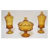 1080	3 PIECES OF AMBER FOSTORIA COIN GLASS, LOT INCLUDES TWO COVERED URNS & A COVERED COMPOTE. URNS 