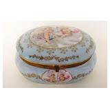 1127	PORCELAIN OVAL HINGED DRESSER BOX W/IMAGES OF CHERUBS & ROSE INTERIOR, APPROXIMATELY 5 IN X 7 I