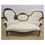 1209	ORNATE WALNUT VICTORIAN SETTEE WITH FLORAL CARVED CREST AND EBONIZED FINISHTRIM AND TUFTED BACK