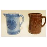 1214	2 STONEWARE PITCHERS, ONE W/EMBOSSED AMERICAN INDIAN & OTHER EMBOSSED W/GRAPES & VINE, APPROXIM