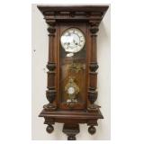 1122	GERMAN WALNUT WALL CLOCK W/ENAMELED FACE APPROXIMATELY 4 IN X 8 IN X 35 IN HIGH
