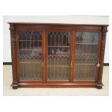 1159	MAHOGANY 3 DOOR LEADED GLASS BOOKCASE W/PINEAPPLE CARVED HALF COLUMNS, ONE PANEL DAMAGED, APPRO