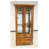 1226	PULASKI OAK 2 DOOR CRYSTAL CABINET WITH LOWER DRAWER AND BEVELED GLASS DOORS WITH SLAG AND ICED