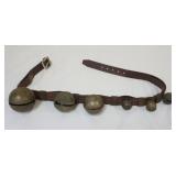 1072	BRASS SLEIGH BELLS, 6 MOUNTED ON LEATHER STRAP, LARGEST APPROXIMATELY 3 1/2 IN