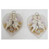 1122	PAIR OF AMART BISQUE HEART SHAPED WALL PLAQUES WITH KISSING CHERUBS MOUNTED ON TOP. EACH APPROX