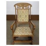 1188	OAK PLATFORM ROCKER WITH CARVED OAK LEAVES, TURNED SPINDLES AND UPHOLSTERED SEAT AND BACK, APPR