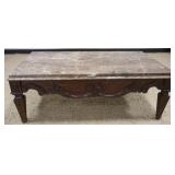 1219	MARBLE TOP COCKTAIL TABLE WITH HEAVY CARVED WOODEN BASE, APPROXIMATELY 52 IN X 32 IN X 19 IN H