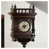 MAHOGANY WALL CLOCK | The carved wood case with turned finials; round clock face with Roman numeral 