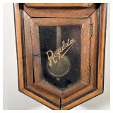 Antique octagonal wall clock with contrasting wood paneling, the face with painted Arabic numerals; 