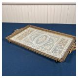 With fancy lace under glass in a silvered footed frame with amethyst-colored jewels and ribbon-form 