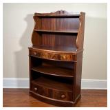 two shelves over a full-width drawer over two shelves and a lower full-width drawer, with carved mot