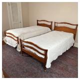 PAIR TWIN MAPLE BEDS | Antique style maple wood beds on casters, with sculpted headboards and footbo