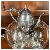 silver on copper tea set, including a teapot, covered sugar, and open creamer, all on an engraved ro
