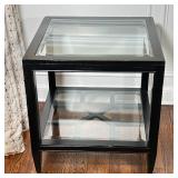 Square side table with a beveled glass top and beveled glass lower shelf over a decorative stretcher
