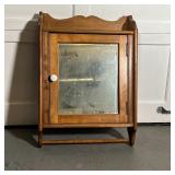 MIRRORED WALL CABINET | Mirrored door with a white porcelain pull, having a shelf on the top and a t