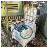 GARDEN HOSE & STORAGE | Green garden hose in a plastic lidded storage wheel