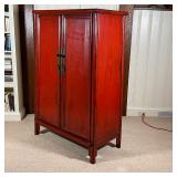 Red lacquered cabinet, with double doors opening to reveal two drawers between open shelves, with br