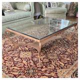 GLASS COFFEE TABLE | Low table with a glass top and a brass toned metal frame with shaped x-stretche