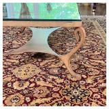 Low table with a glass top and a brass toned metal frame with shaped x-stretcher; h. 19 x 50 x 34 in