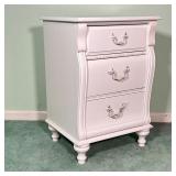 White painted bedside table having three drawers with antique style pulls; h. 29 x w. 20 x d. 17 in.