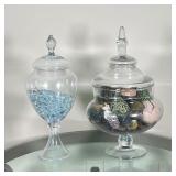 (2pc) LIDDED GLASS JARS | Covered glass jars, one with Elements label and one with Manerisms label; 